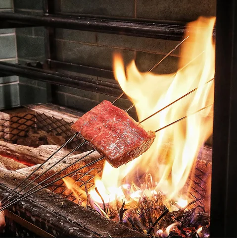 炭火で炙られ表面に焼き色が入る薄切り和牛